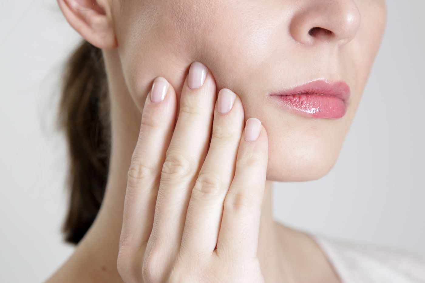 Woman holding her cheek in discomfort from a dental emergency in Santa Barbara CA