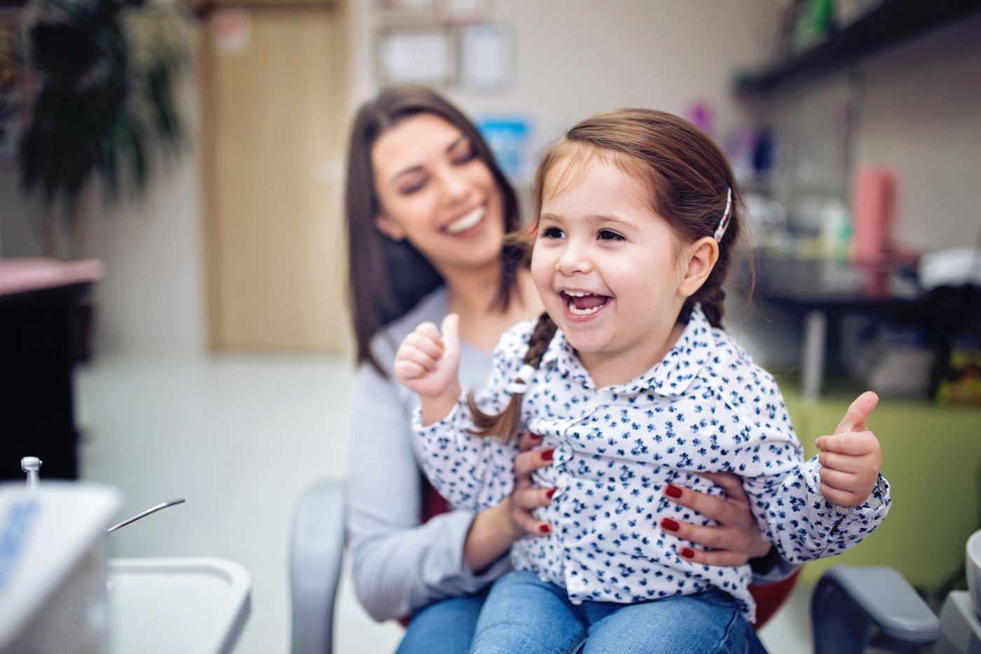 A mother holding her smiling daughter at a family dental visit