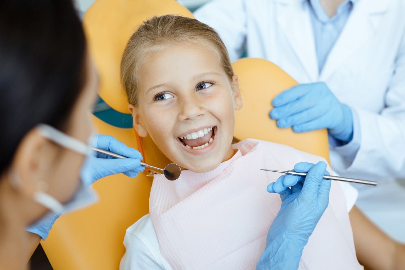 Dentist examining child's teeth with dental instruments in office